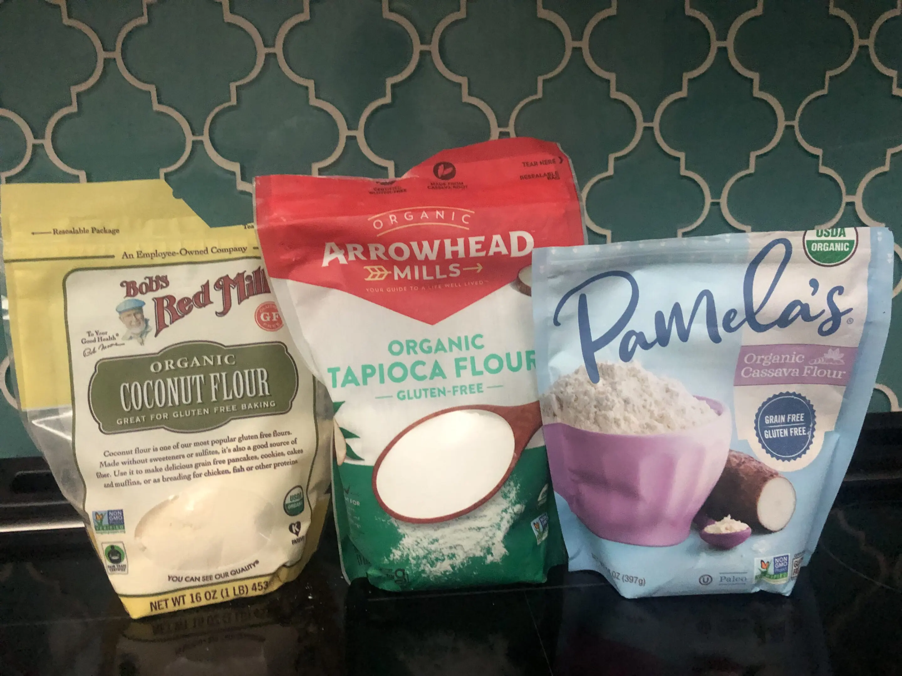 Three different gluten-free flours displayed on a kitchen counter.